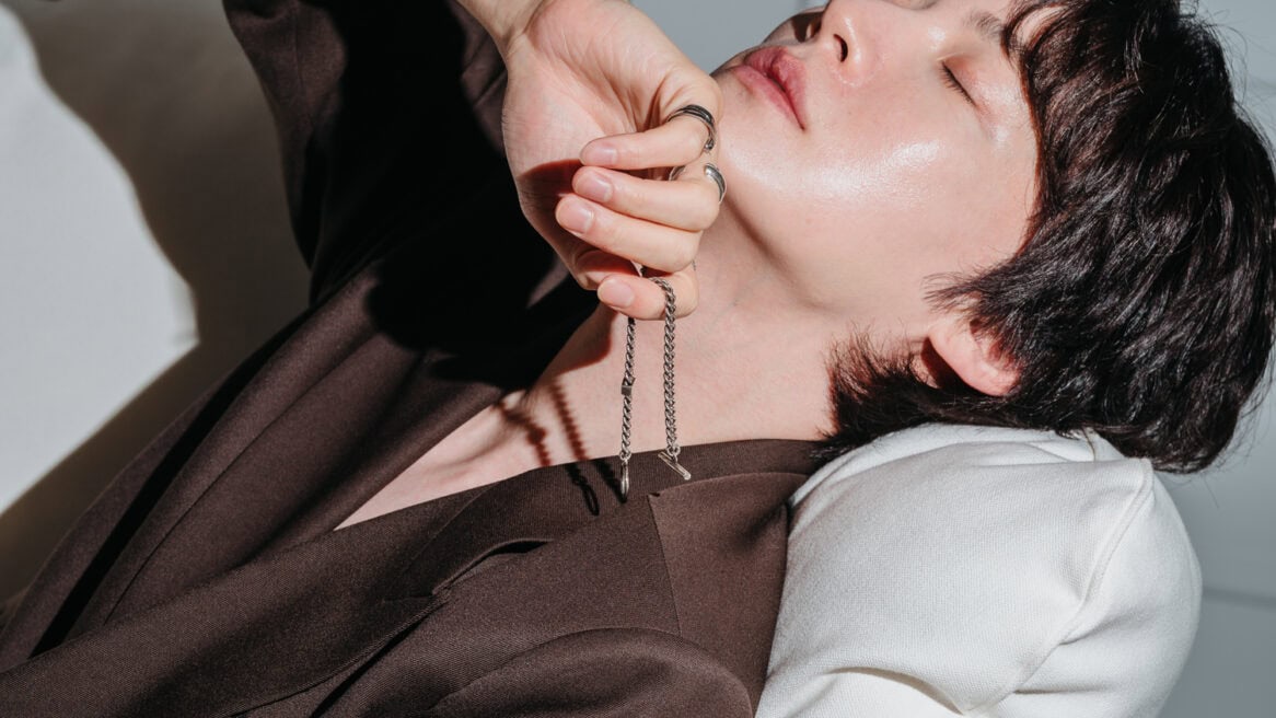 South Korean star Ahn Jae-hyeon is directed by Seoul photographer Jun Michael Park in a portrait setting to lean back and close his eyes, while holding a necklace that he designed close to his face.